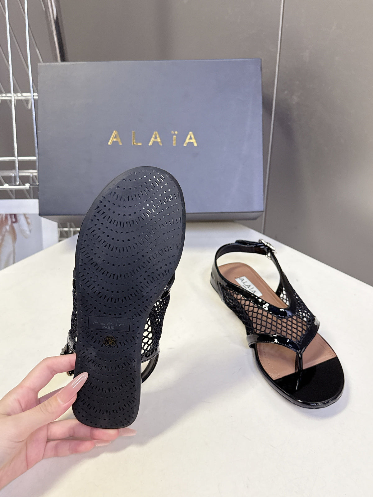 ALAIA 26S FLAT MESH THONG SANDALS IN BLACK PATENT CALFSKIN