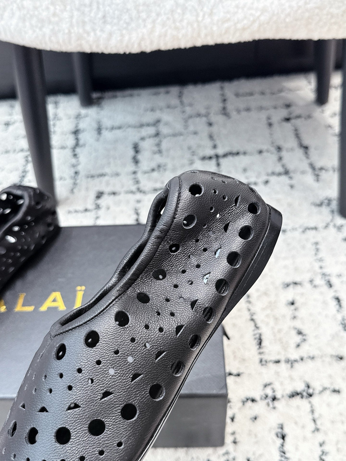ALAIA 26S FLAT SLIP-ONS IN BLACK CALFSKIN WITH OPENWORK PATTERN